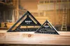 Two black metal squares with measurement markings are placed on a wooden plank, with a workshop background. Voir les images du produit