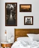 A bedroom scene with framed pictures on the wall above a wooden headboard and a bedside table with a lamp. Produktbild-Vorschau