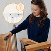 A woman is shown interacting with a baby gate, possibly installing or securing it. Voir les images du produit
