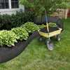 A garden scene with a raised flower bed, a wheelbarrow filled with soil, and a shovel. Produktbild-Vorschau