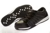 A pair of black safety shoes with white stitching and white soles, shown from a slightly angled perspective. One shoe is upright, and the sole of the other shoe is visible. Produktbild-Vorschau