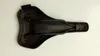 The underside of a black bicycle saddle is shown on a white background. Produktbild-Vorschau