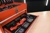 A close-up view of an open red toolbox filled with various tools, including a red electric screwdriver and numerous bits. Produktbild-Vorschau