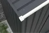 Close-up view of a white gutter attached to a dark gray metal shed roof. Produktbild-Vorschau