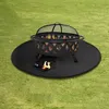 A fire pit sits on a black mat on a grassy lawn. Produktbild-Vorschau