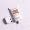 A tube of GUINOT Crème Youth Perfect Finish SPF 50 is shown on a striped background with the cap off. Produktbild-Vorschau