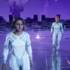 Two women in futuristic white suits stand in a purple, digital-like environment. Podgląd zdjęcia produktu