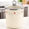 A cream-colored storage container with a glass lid and a decorative heart pattern sits on a countertop in a kitchen setting. Produktbild-Vorschau