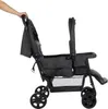 A hand is holding the handle of a twin stroller. Produktbild-Vorschau