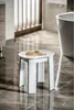 A white stool with two hairbrushes on top, placed on a tiled floor in a bathroom next to a bathtub. Anteprima dell’immagine prodotto