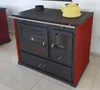 A red and black wood-burning stove with a yellow kettle on top, placed on a tiled floor. Produktbild-Vorschau