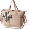 A studio shot of a beige diaper bag with a patterned scarf tied to the handle. Produktbild-Vorschau