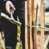 A person is using a tool to attach wire to wooden fence posts. Voir les images du produit