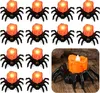 A collection of 12 spider-shaped LED candles arranged in rows on a white background, with one candle shown in detail in the lower right corner on a wooden surface. Náhled obrázku produktu