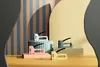 Four colorful staplers are arranged on geometric platforms against a striped background. Podgląd zdjęcia produktu