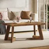 A rustic wooden coffee table is placed in a living room setting, in front of a sofa with decorative pillows and a vase of flowers. Podgląd zdjęcia produktu