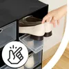 A hand is placing a shoe into a black shoe storage box. Podgląd zdjęcia produktu
