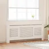 A white radiator cover is placed in front of a window with white blinds. Podgląd zdjęcia produktu