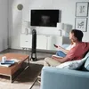 A couple sits on a couch in a living room, watching TV. A tower fan is placed in the corner. Podgląd zdjęcia produktu