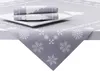 A folded tablecloth with a snowflake and tree pattern is placed on a white plate on top of a larger tablecloth with the same pattern. Produktbild-Vorschau