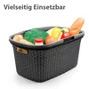A black woven basket filled with groceries, including broccoli, bread, tomatoes, and a bottle of milk. Produktbild-Vorschau