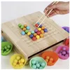 A hand using chopsticks to pick up a red bead from a wooden board with many colorful beads arranged in a pattern. Several colorful silicone cups filled with beads are around the board. Voir les images du produit