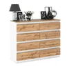 A dresser with eight drawers is shown against a white background. The dresser has a white frame and drawers with a wood grain finish. Decorative items are placed on top of the dresser, including a lamp, picture frames, a vase of flowers, and decorative obj Produktbild-Vorschau