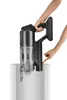 A person is holding a cordless vacuum cleaner and emptying its dustbin into a container. Produktbild-Vorschau