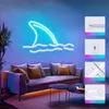A living room with a neon shark fin sign on the wall above a sofa, with LED strip lights under the sofa and coffee tables. Produktbild-Vorschau