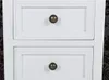 A close-up view of two white drawers with dark metal knobs. Náhled obrázku produktu