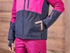 A person wearing a pink and navy blue ski jacket and pink ski pants, with their hand in the jacket pocket. Produktbild-Vorschau