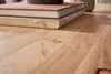 A close-up view of a wooden table with two books stacked on top. Produktbild-Vorschau