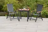 A patio set with two chairs and a table on a tiled patio, with greenery in the background. Produktbild-Vorschau