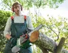 A man is using a cordless chainsaw to cut a log in a garden setting. Produktbild-Vorschau