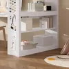 A white shelf unit with various items on it, including books, boxes, and decorative items. The shelf is placed in a room with a wooden floor and a rug. Náhled obrázku produktu