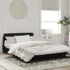 A bedroom scene with a black bed frame and white bedding. Produktbild-Vorschau