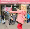 Kind in einer pinken Jacke, das eine pink-weiße Bazooka-Blasenpistole hält und viele Blasen im Freien bläst Voir les images du produit