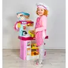 A young girl dressed as a chef stands next to a toy kitchen playset. Náhled obrázku produktu