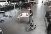 A man is working on a car part in a garage. Produktbild-Vorschau