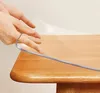 Hands are shown placing a transparent protective sheet on a wooden table. Náhled obrázku produktu