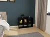 A black cube shelf unit is placed against a dark blue wall in a bedroom setting, with a bed on the left and a curtain on the right. Produktbild-Vorschau