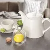 A tea set with macarons and fruit on a table. Náhled obrázku produktu