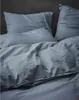 A close-up view of rumpled blue bedding, including pillows and a duvet cover. Produktbild-Vorschau