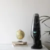 A black handheld vacuum cleaner is displayed on a white surface next to a globe and books. Voir les images du produit