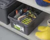 A storage box filled with fishing lures is placed on a shelf next to a pair of yellow boots. Anteprima dell’immagine prodotto