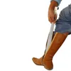 A person is using a shoehorn to put on a brown boot. Podgląd zdjęcia produktu