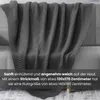 A dark gray knitted blanket draped over a sofa. Náhľad obrázku produktu