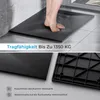 A person's feet are shown standing on a black shower tray in a bathroom setting. Náhled obrázku produktu