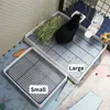 Two pet litter boxes, one large and one small, are shown. A black rabbit is in the larger litter box, which contains hay. A water bottle is attached to the side of the cage. Produktbild-Vorschau