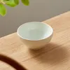A light gray ceramic bowl with vertical ridges sits on a wooden surface, with green leaves in the upper left corner. Produktbild-Vorschau